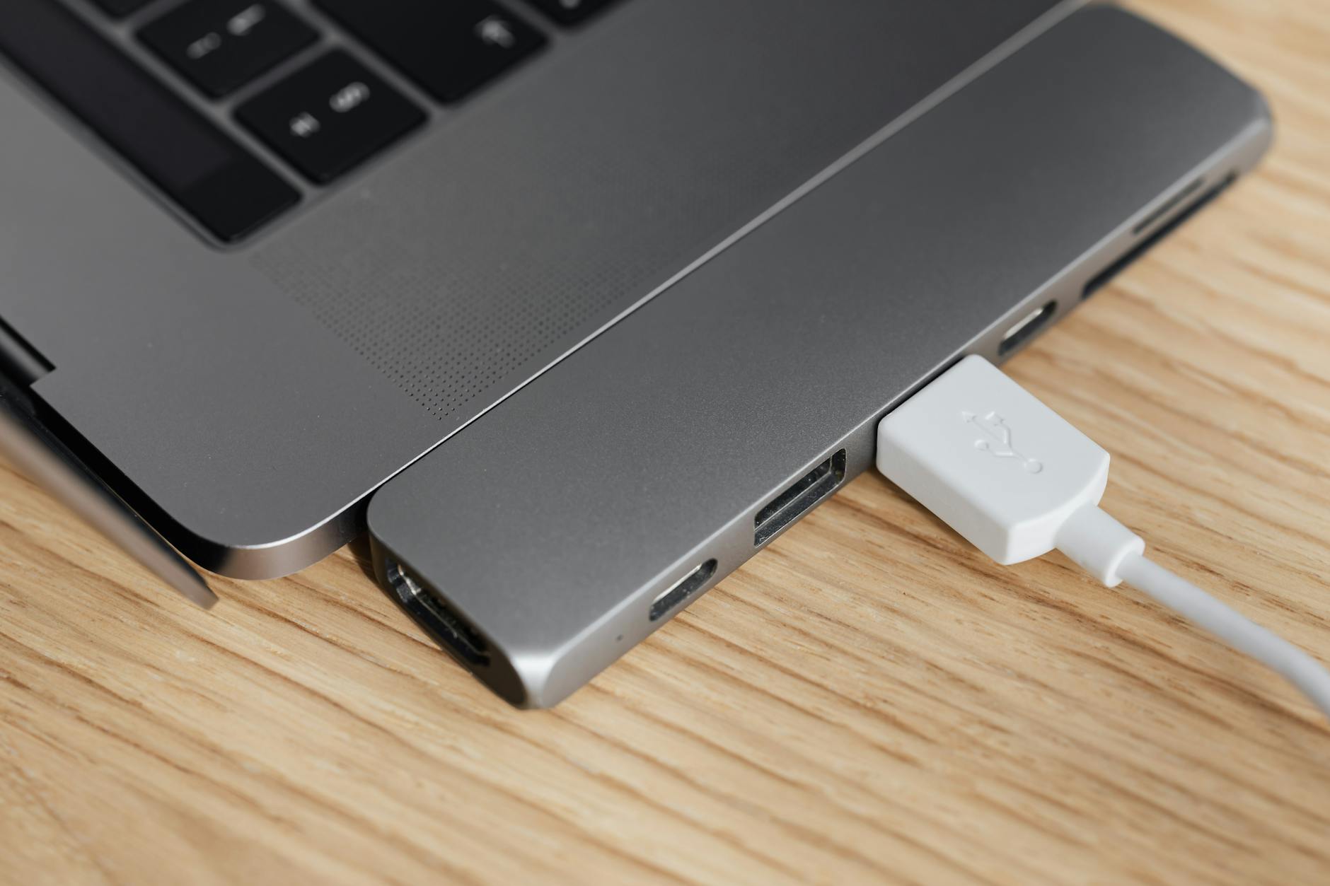Hub USB-C podłączony do laptopa na drewnianym biurku
