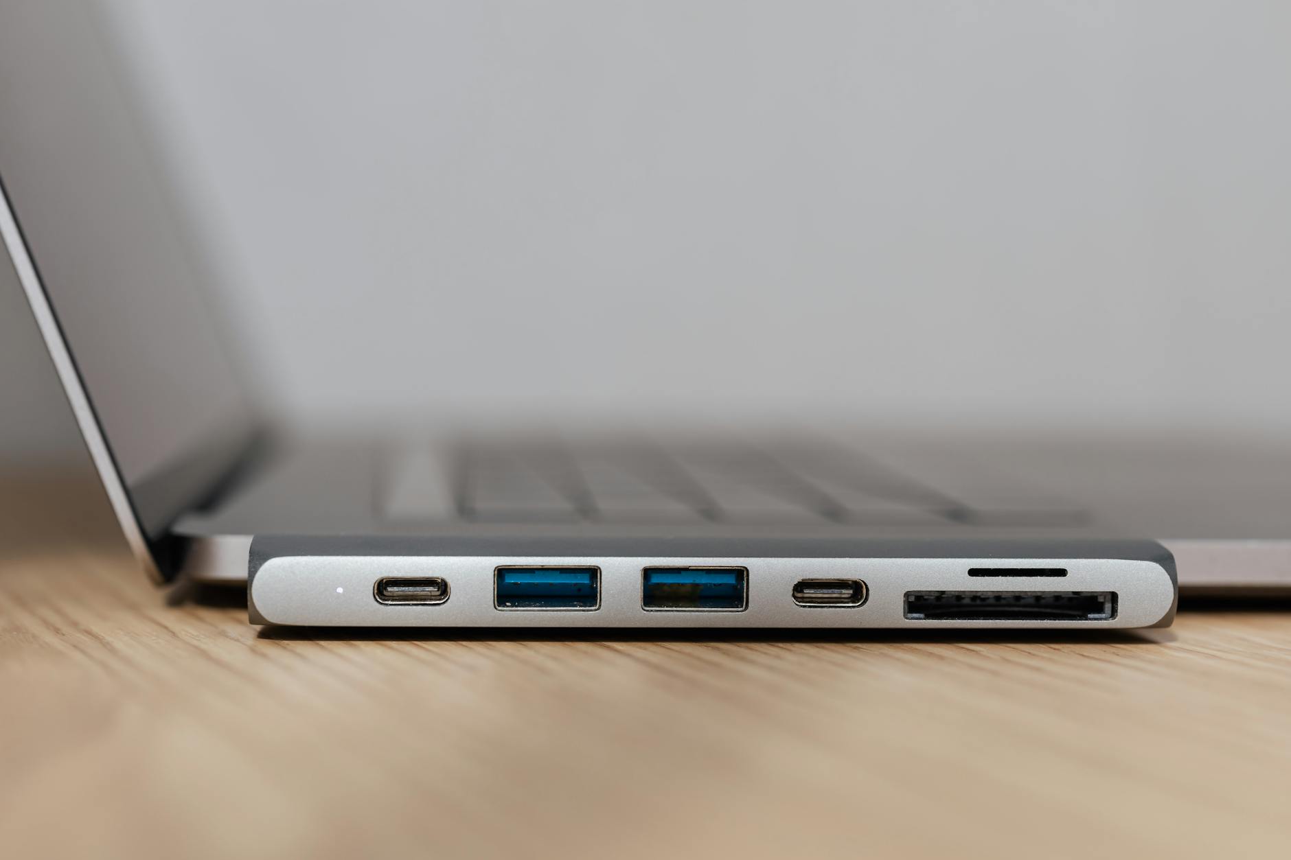 Szary hub USB-C z wieloma portami podłączony do laptopa