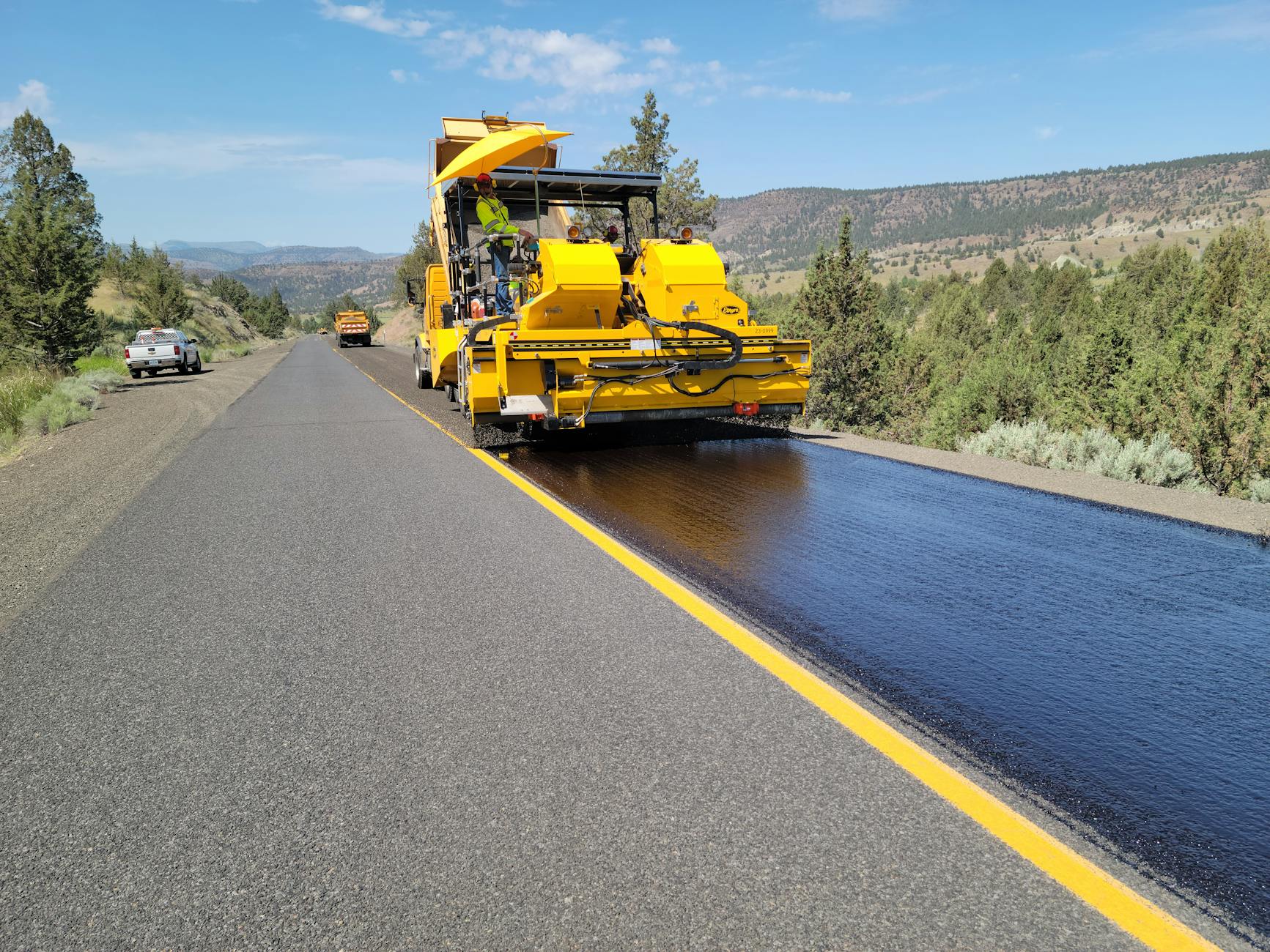 Maszyna układająca asfalt na wiejskiej drodze w trakcie budowy
