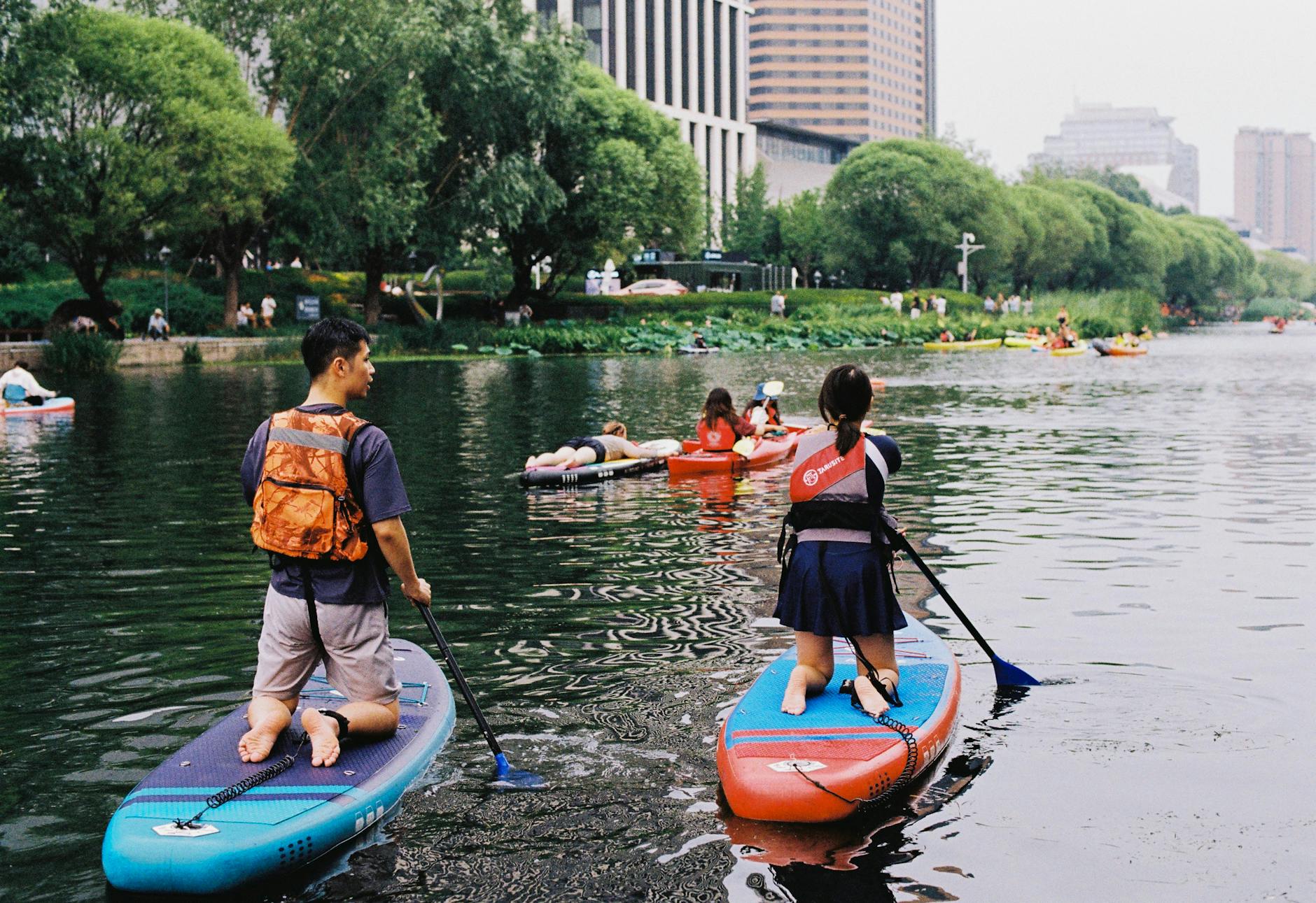 Rodziny na deskach SUP płynące spokojną rzeką w miejskim parku