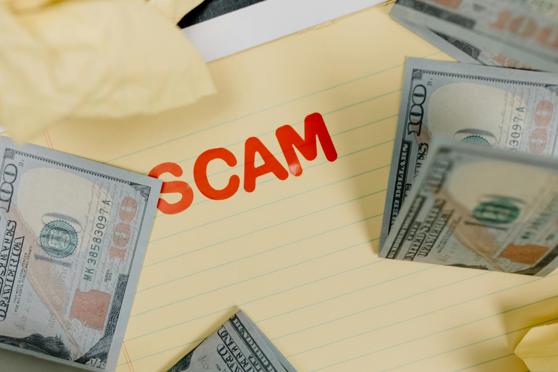 Banknoty dolarowe na żółtym tle z napisem scam