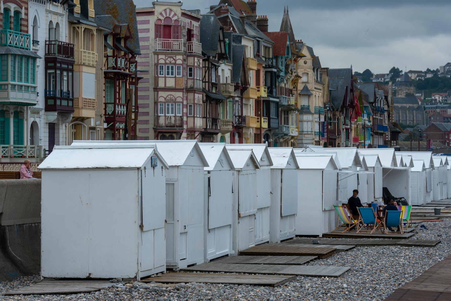 Kolorowe domki plażowe nad kamienistą plażą w europejskim miasteczku