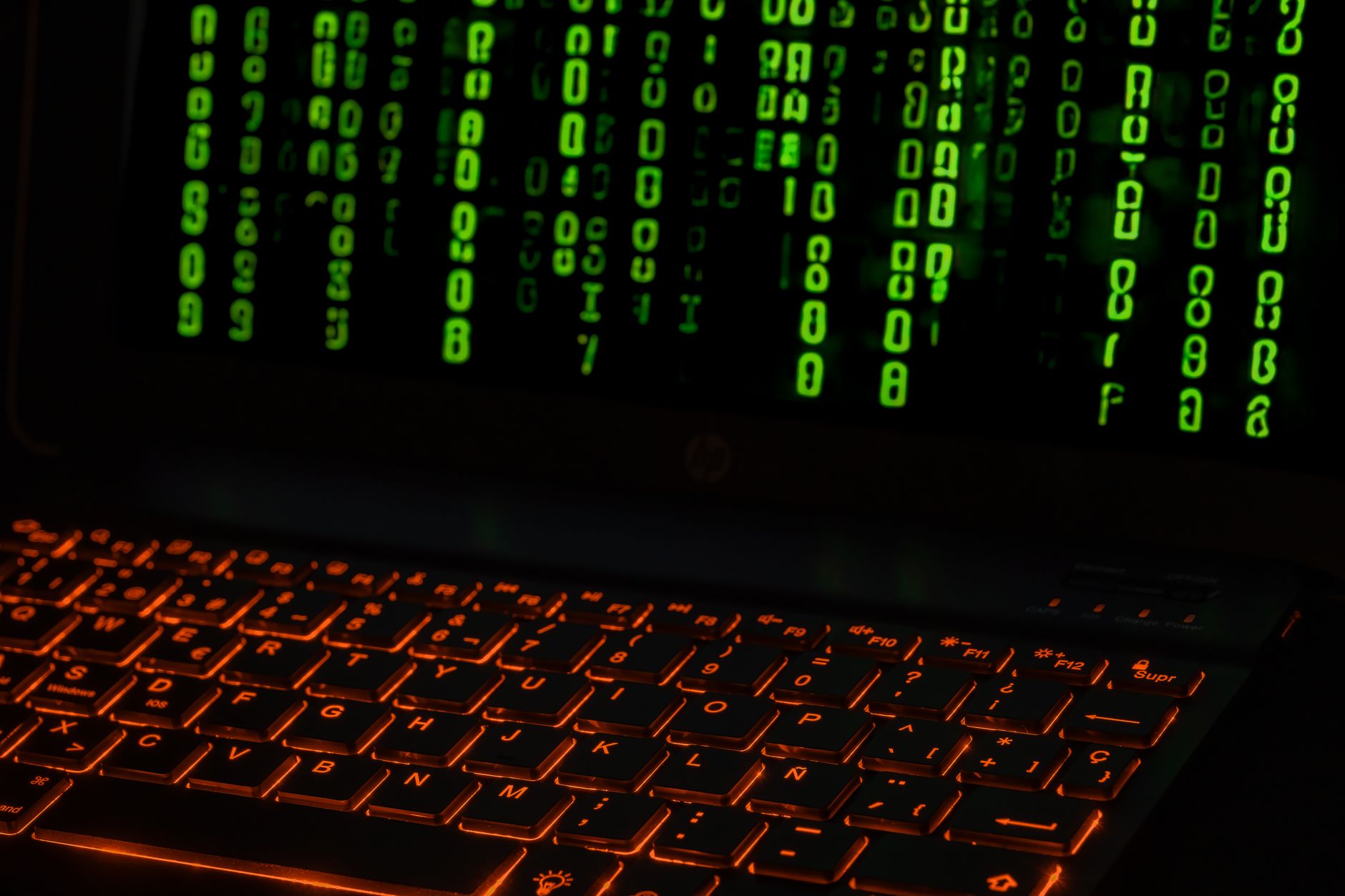 Praca zdalna w 2026 Jak mądrze łączyć VPN chmurę i narzędzia online dla bezpieczeństwa Klawiatura laptopa z pomarańczowym podświetleniem i zielonym kodem na ekranie