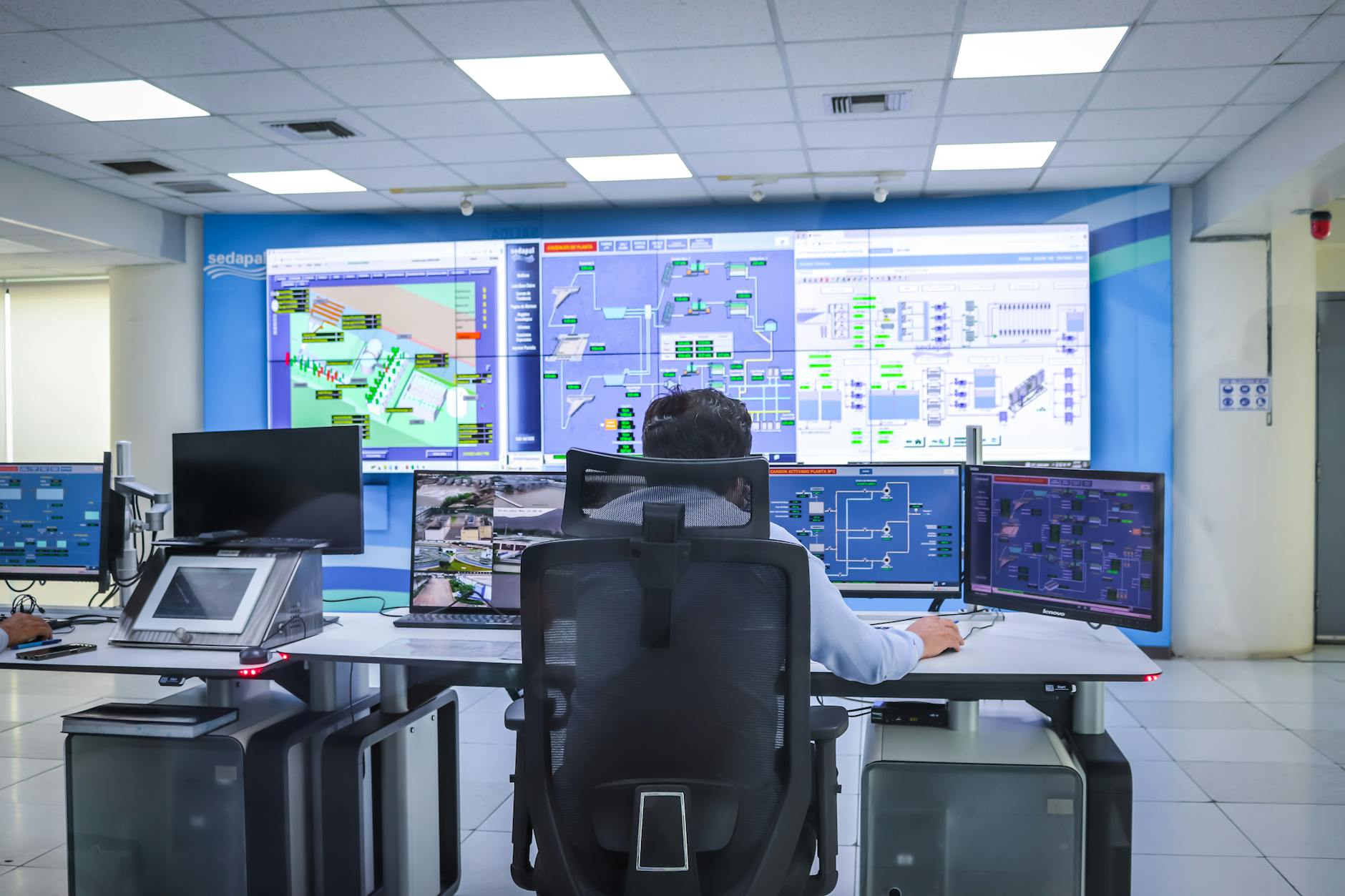 Operator przy wielu monitorach w nowoczesnej sali kontrolnej