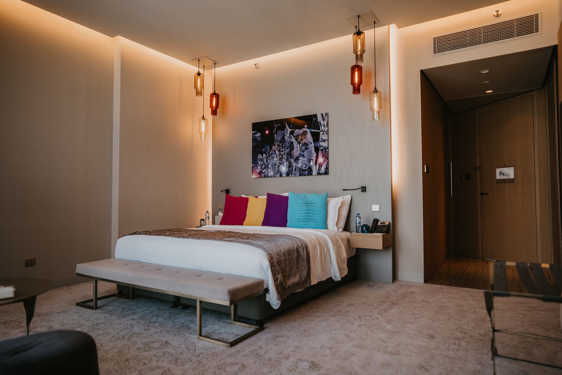 Przestronna sypialnia hotelowa z kolorowymi poduszkami i luksusowym wystrojem