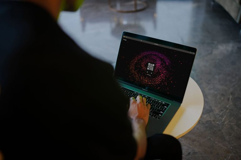 Osoba korzystająca z laptopa z kolorowym kodem QR na ekranie